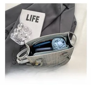 Detail view of woven handbag interior holding a folded umbrella and a smartphone