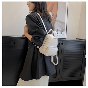 Mini white leather backpack worn by model showing adjustable straps and compact design