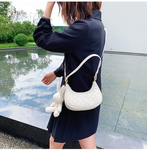 Détail du sac croissant blanc avec motif en M et breloque lapin en peluche attachée