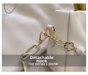 Détail du crochet doré amovible et de la chaîne de perles sur le sac plissé ivoire