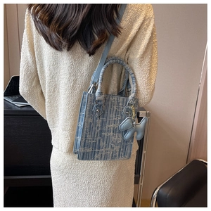 Blue woven crossbody bag featuring a leather dog charm and matching shoulder strap