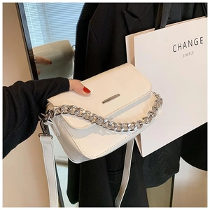 Detail view of a white leather crossbody bag featuring silver chain and metal bar accents