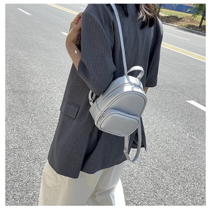 Close-up of light gray mini PU leather backpack showing fine texture and zipper details