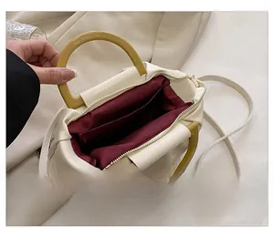 Détail de l'intérieur du sac nuage crème avec doublure bordeaux et chaîne dorée