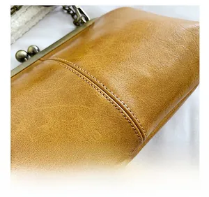 Close-up of precision stitching and mustard yellow leather texture on shell bag
