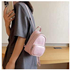 Mirror selfie showing a mini pink leather backpack with zipper pockets on grey blazer outfit