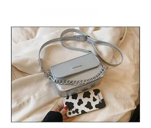 Detailed size comparison of a silver glitter crossbody bag next to a smartphone