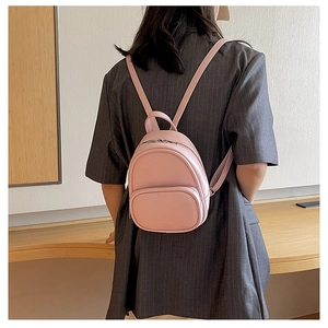 Pink mini faux leather backpack worn by model showing small size and modern style