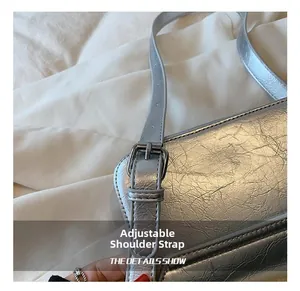 Detail view of silver crossbody bag with adjustable metallic strap and retro buckle