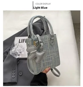Detail of light blue woven handbag with matching leather handle and cute puppy charm