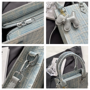 Detail view of light blue woven tote bag with silver zippers and a cute puppy charm