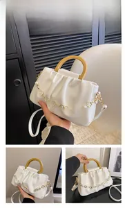 Détail du sac nuage blanc avec poignée en résine jaune et breloque trèfle en perles