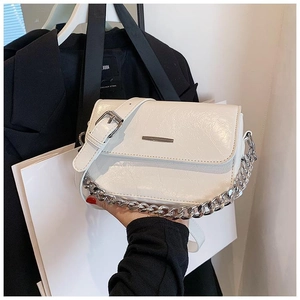 Close-up of off-white wrinkled leather crossbody bag with silver chain and metal bar