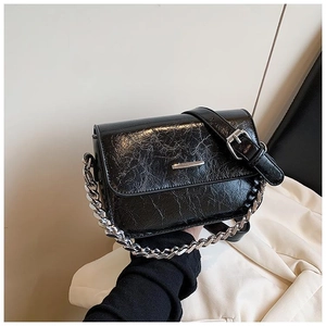 Close-up of black crossbody bag with cracked leather texture and silver chain strap