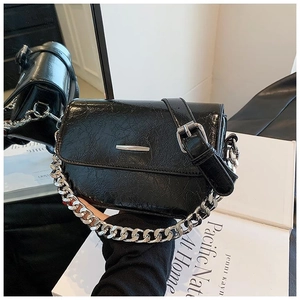 Detail of black crossbody bag with silver chain handle and textured pleated finish