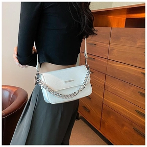 Detailed side view of a white leather crossbody bag with silver chain and shoulder strap