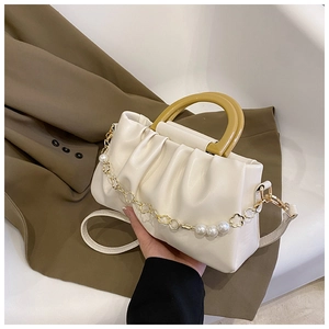 Détail du sac nuage plissé beige avec poignée en résine et chaîne de perles décorative