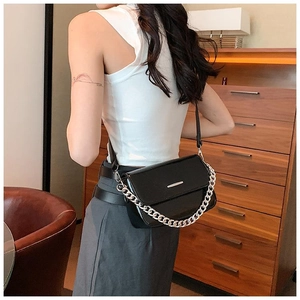 Detail of a chic black crossbody bag with silver chain and metal bar on the front cover