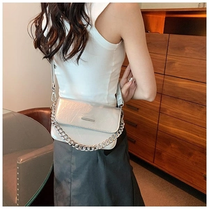 Silver textured crossbody bag with metal chain strap shown on model in indoor setting