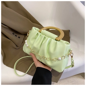 Détail du sac plissé vert menthe avec poignée en bois et chaîne de fleurs perlées