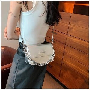 Silver crescent crossbody bag with metal chain detail shown on a person in a casual setting