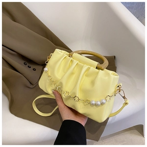 Détail du sac nuage plissé jaune clair avec anse en résine et chaîne dorée fleurie