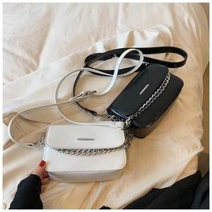 Detail of minimalist black and white square bags with silver chain and metal bar accents