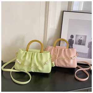 Détail de sacs plissés vert et rose avec poignées en bois et chaîne florale dorée