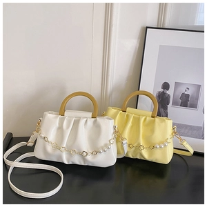 Détail de sacs plissés avec poignées en bois et chaînes de perles métalliques