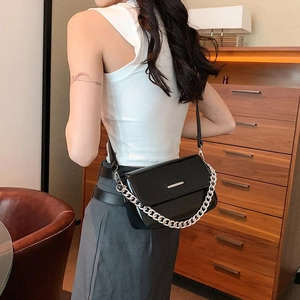 Fashionable black crossbody flap bag with silver chain and leather strap on a model