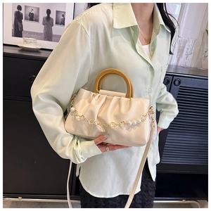 Détail d'un sac nuage blanc crème avec poignée en bois et chaîne de fleurs en perles
