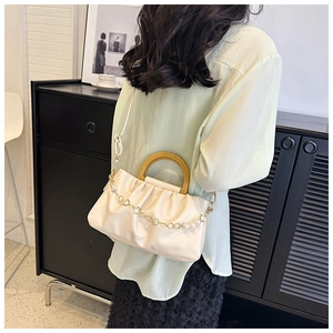 Sac nuage plissé avec poignée en bois et chaîne de perles porté par un mannequin en bandoulière