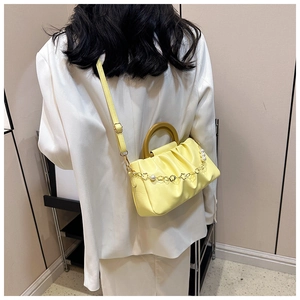 Détail du sac nuage jaune avec poignée en bois et chaîne de fleurs en perles sur modèle