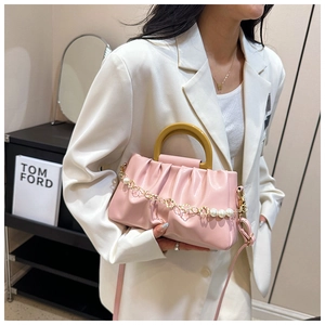 Détail du sac nuage plissé rose avec poignée en résine jaune et chaîne de perles élégante