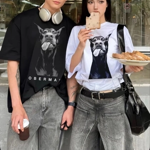 Couple portant des T-shirts amples en coton avec imprimé Doberman dans un décor urbain