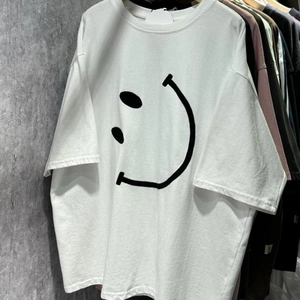 Vue détaillée du grand imprimé smiley noir sur le t-shirt blanc en coton ample