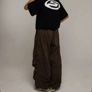 Back view of black Y2K t-shirt with white circular logo and brown cargo pants