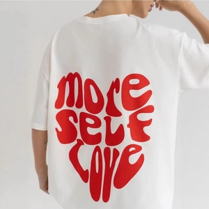 T-shirt in cotone bianco con grafica a cuore rossa 'MORE SELF LOVE' stampata sul retro