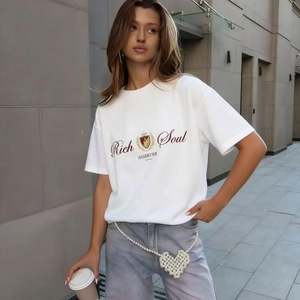 Détail d'un t-shirt blanc en coton avec imprimé 'Rich Soul' et chaîne de taille perle cœur