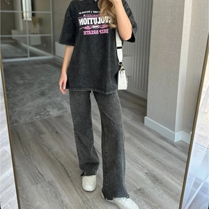 Détail d'un t-shirt en coton noir délavé avec motif rose et un jean en denim à paillettes