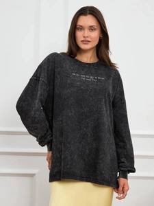 Detail of vintage washed black oversized sweatshirt with white inspirational text print