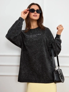 Close-up of vintage washed black cotton long sleeve T-shirt with white graphic text print