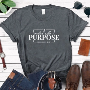 Flat lay of charcoal gray bible t-shirt with Ephesians 2:10 quote and fashion accessories