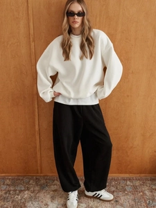 Oversized white round neck sweatshirt with high-waist black wide-leg trousers and sneakers