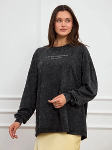 Detail of mineral wash texture and white typography print on oversized charcoal long sleeve tee