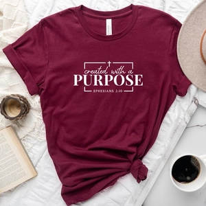 Flat lay of wine red cotton T-shirt with white religious print and lifestyle props