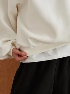 Close-up of white heavyweight cotton sweatshirt showing soft fabric and ribbed cuffs
