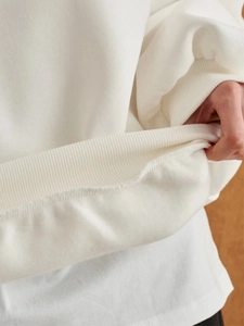 Close-up of elastic ribbed hem on a thick white crewneck sweatshirt showing fabric detail
