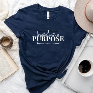 Flat lay of navy cotton T-shirt with Created with a Purpose text and casual accessories