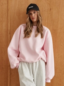 Detail view of pink oversized sweatshirt paired with grey joggers and a black baseball cap